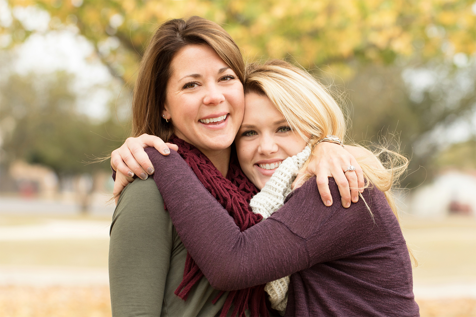 Mother and her daughter embrace, while smiling towards the camera. 